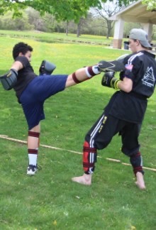 Teenage boys sparring, one high kicking the other